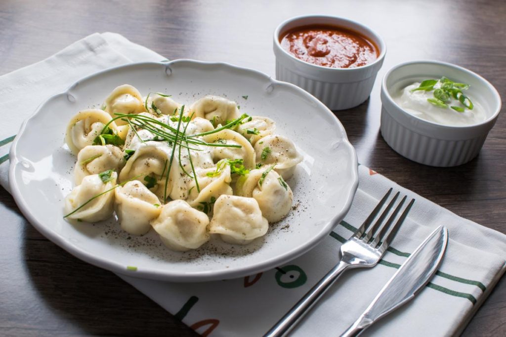 Siberian pelmeni served with sour cream and pepper